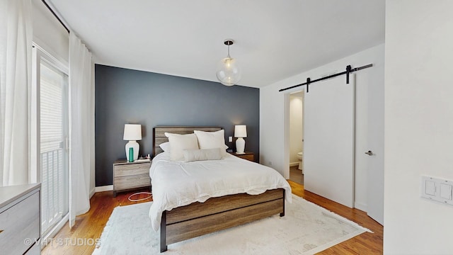 1341 N Wolcott Ave Unit A, Chicago, IL 60622 - bedroom with a barn door, light wood-type flooring, and ensuite bath