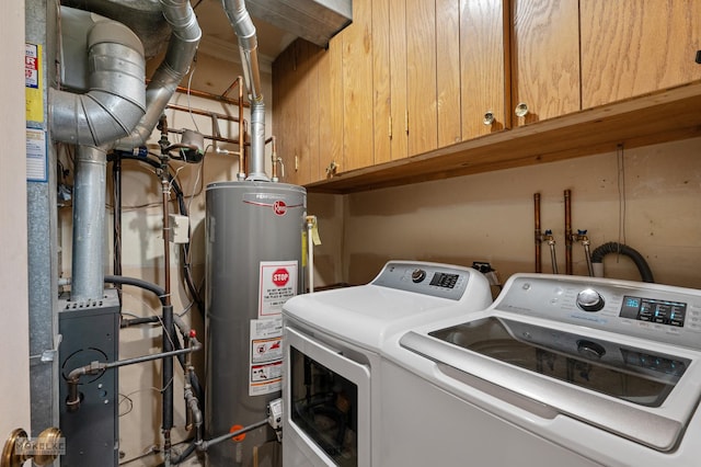 clothes washing area featuring heating unit, cabinet space, water heater, and washer and dryer