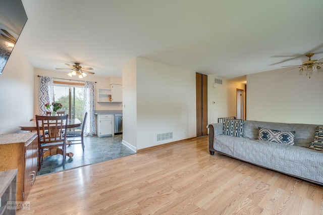 living room with a ceiling fan, visible vents, and light wood finished floors