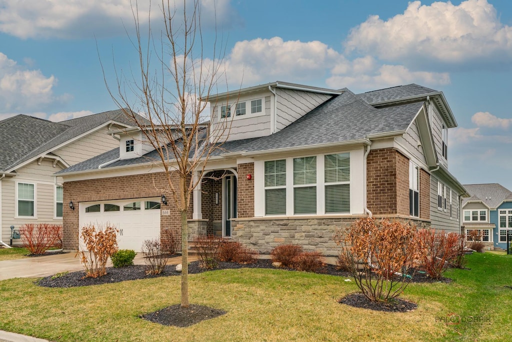 view of front of house with a garage, brick siding, driveway, and a front lawn