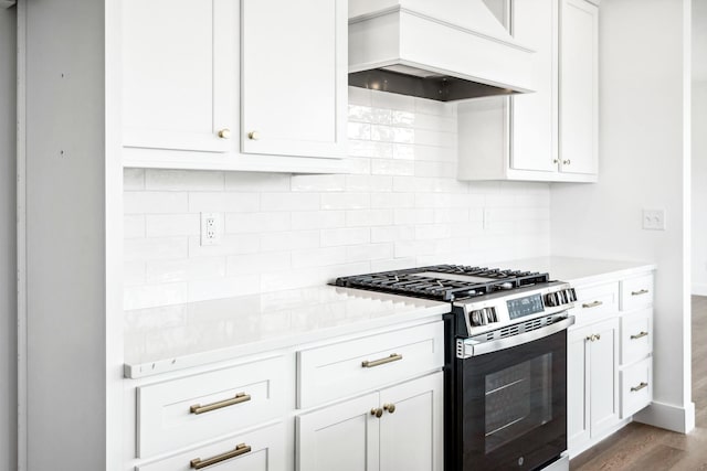 kitchen with dark wood-style flooring, premium range hood, stainless steel gas range oven, light countertops, and backsplash