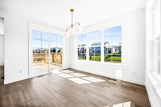 interior space with visible vents, baseboards, a chandelier, and wood finished floors