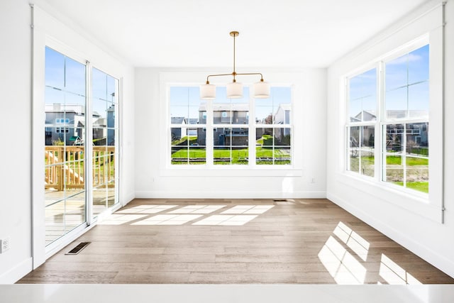unfurnished sunroom with visible vents, an inviting chandelier, and a healthy amount of sunlight