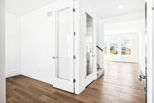 corridor featuring stairs, visible vents, baseboards, and wood finished floors