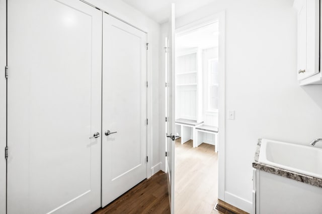 interior space featuring white cabinets, dark wood-style floors, baseboards, and a sink