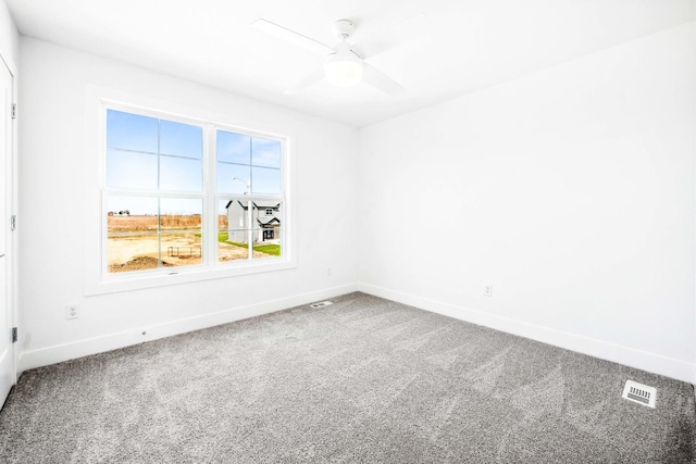 carpeted empty room with baseboards, a ceiling fan, and visible vents