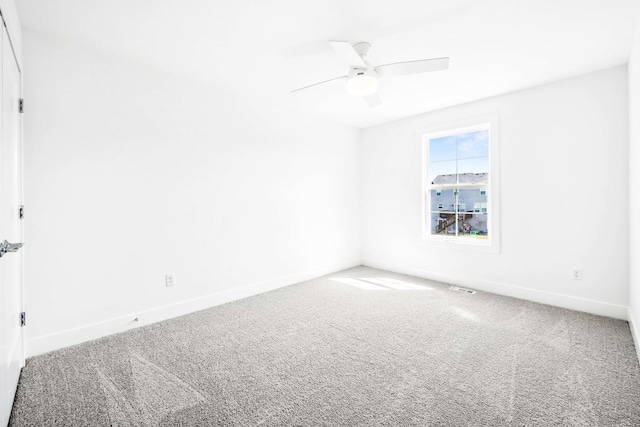 carpeted empty room with visible vents, baseboards, and a ceiling fan