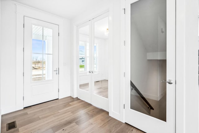 foyer entrance featuring french doors, wood finished floors, and visible vents