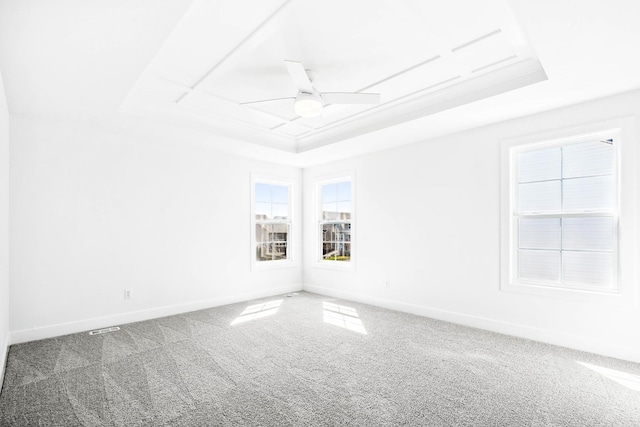 carpeted empty room featuring a tray ceiling, baseboards, and ceiling fan