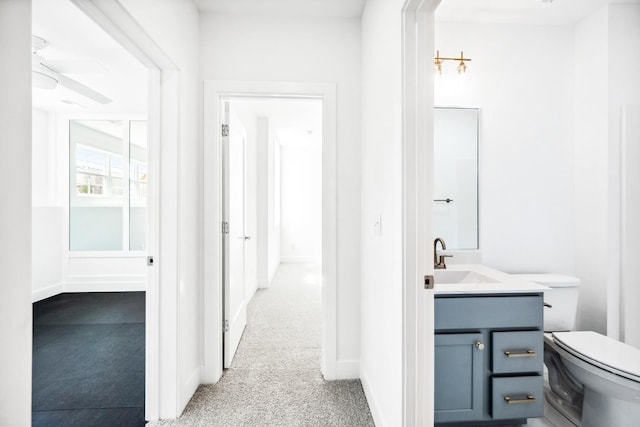 hallway with baseboards, a sink, and carpet floors