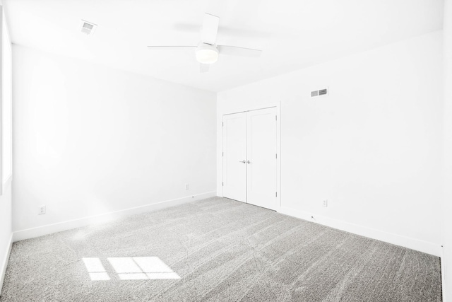 carpeted empty room with visible vents, ceiling fan, and baseboards