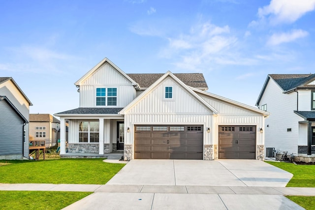 view of front of home with stone siding, a garage, board and batten siding, a front lawn, and driveway