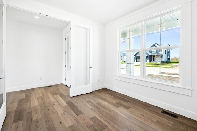 unfurnished room featuring visible vents, baseboards, and wood finished floors
