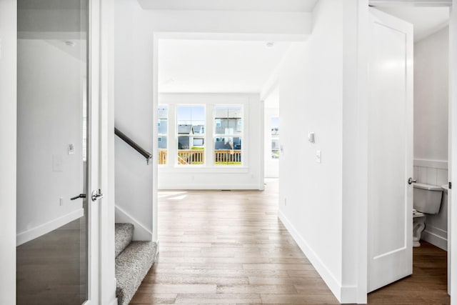 hallway with wood finished floors, baseboards, and stairway