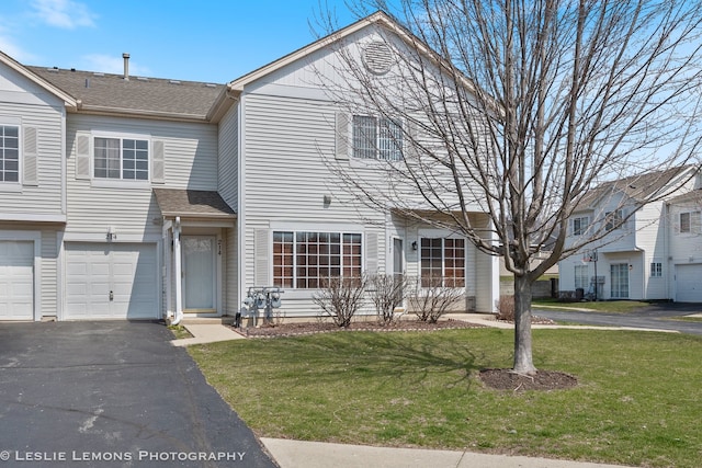 view of property featuring a front yard, a shingled roof, driveway, and an attached garage