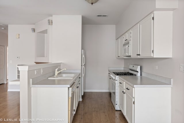 kitchen featuring baseboards, white appliances, visible vents, a sink, and wood finished floors