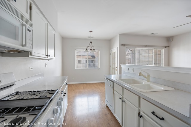 kitchen featuring white appliances, light wood-style flooring, light countertops, white cabinets, and a sink