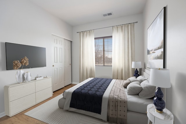 bedroom featuring visible vents, baseboards, light wood-type flooring, and a closet