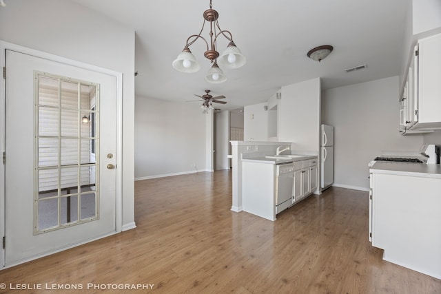 kitchen featuring visible vents, white cabinets, white appliances, light wood-style floors, and ceiling fan with notable chandelier