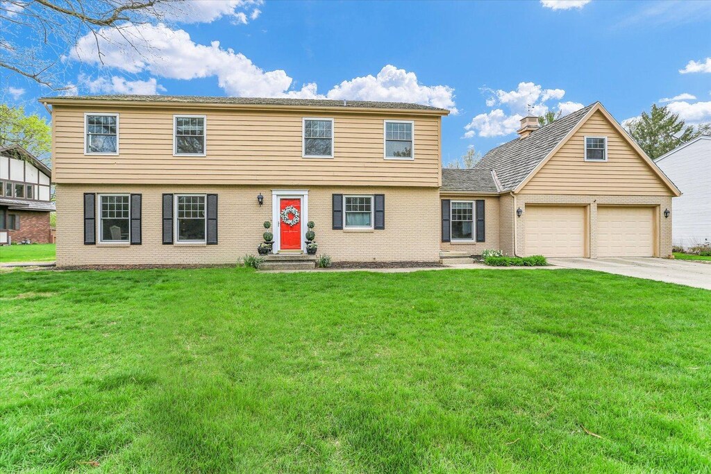 1917 Woodfield Rd, Champaign, IL 61822 - colonial-style house featuring a front lawn, driveway, and a garage