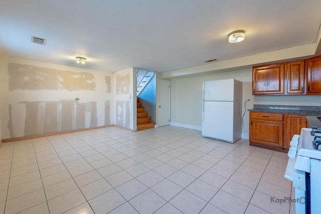 kitchen with visible vents, brown cabinetry, dark countertops, and white appliances