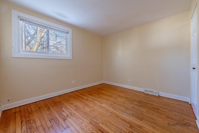 unfurnished room with light wood finished floors, visible vents, and baseboards