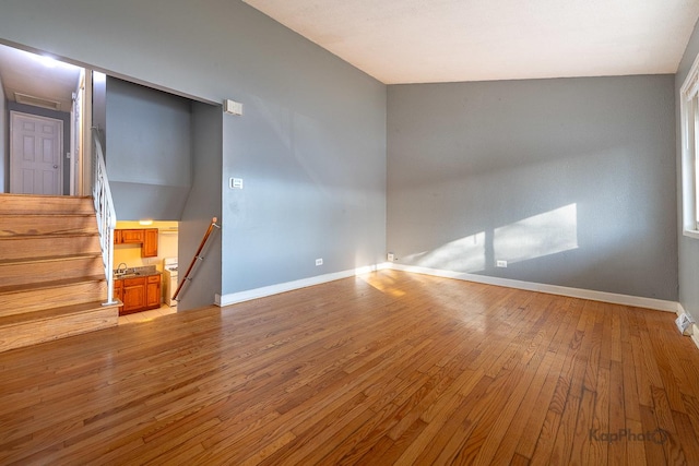 empty room with light wood-style floors, baseboards, and a sink
