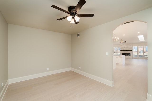 unfurnished room with visible vents, ceiling fan, light wood-type flooring, and arched walkways