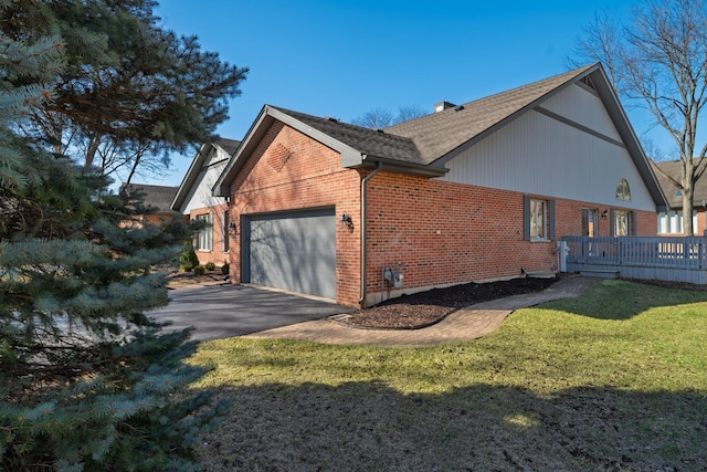 view of side of home featuring a shingled roof, a yard, a garage, brick siding, and driveway