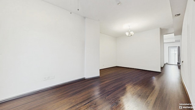 empty room with dark wood-style floors and an inviting chandelier