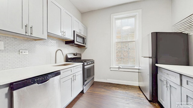 kitchen featuring tasteful backsplash, baseboards, light countertops, stainless steel appliances, and a sink