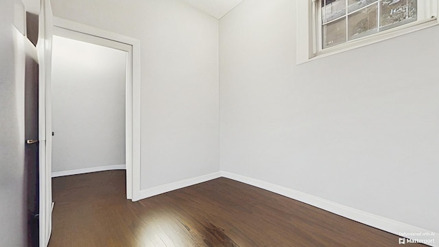 unfurnished room with baseboards and dark wood finished floors