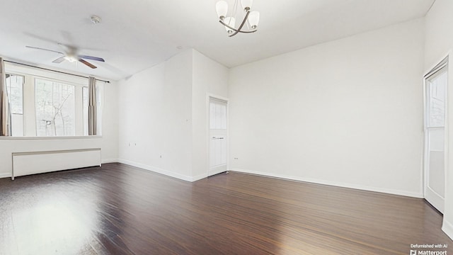 empty room with dark wood-type flooring, radiator, ceiling fan with notable chandelier, and baseboards