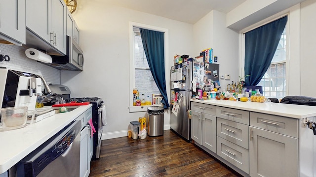 kitchen with stainless steel appliances, plenty of natural light, dark wood-style flooring, and gray cabinets