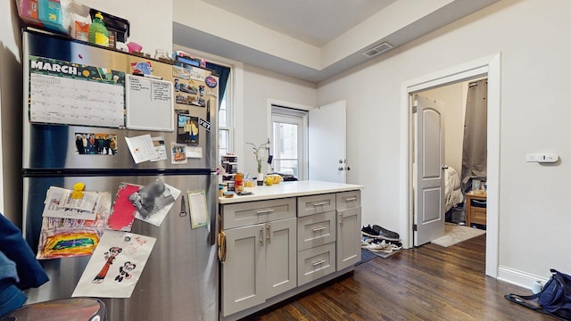 kitchen with visible vents, light countertops, freestanding refrigerator, gray cabinetry, and dark wood-type flooring