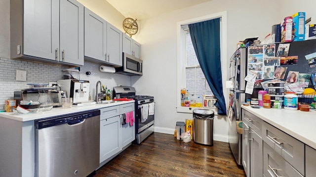 kitchen featuring dark wood-type flooring, appliances with stainless steel finishes, gray cabinetry, and backsplash