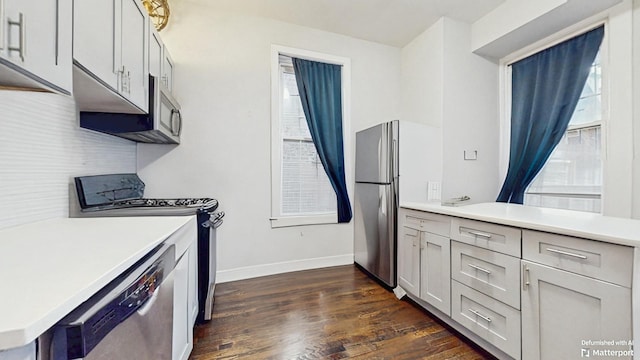 kitchen with stainless steel appliances, dark wood-style flooring, light countertops, and baseboards