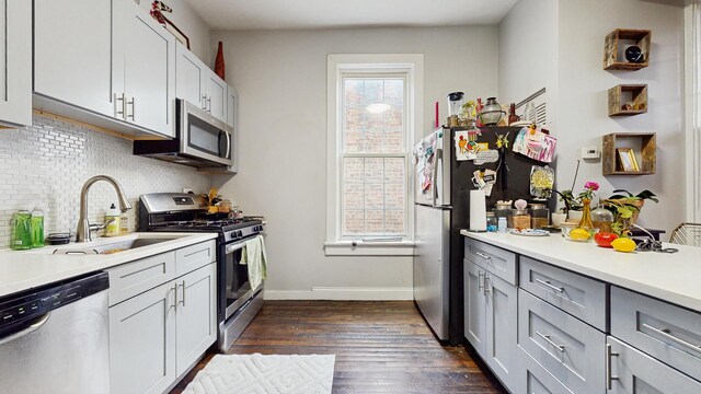 kitchen with a wealth of natural light, dark wood finished floors, a sink, and appliances with stainless steel finishes