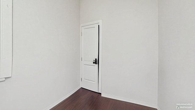 spare room featuring dark wood-type flooring and baseboards