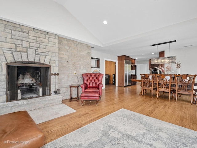 living room with a stone fireplace, recessed lighting, wood finished floors, and lofted ceiling
