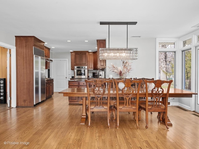 dining space with recessed lighting, baseboards, a chandelier, and light wood-type flooring