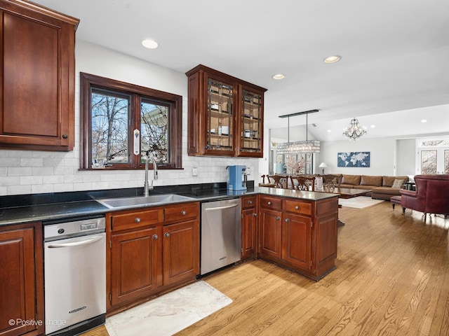 kitchen with dark countertops, open floor plan, light wood-type flooring, a sink, and dishwasher