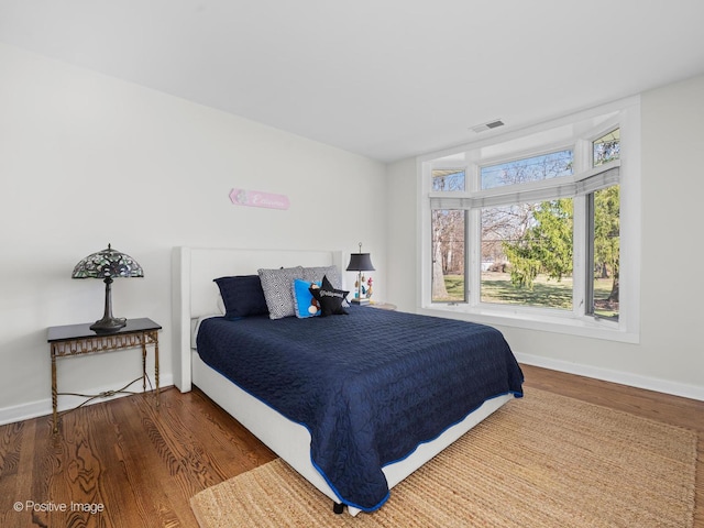 bedroom with visible vents, baseboards, and wood finished floors