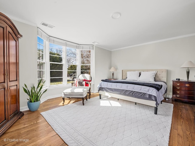 bedroom featuring ornamental molding, visible vents, multiple windows, and wood finished floors