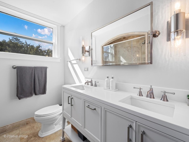 bathroom featuring double vanity, a sink, walk in shower, and toilet