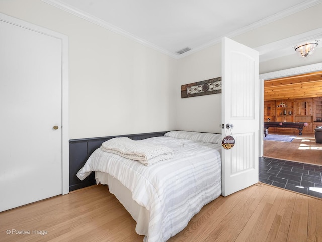 bedroom with crown molding, visible vents, and wood finished floors