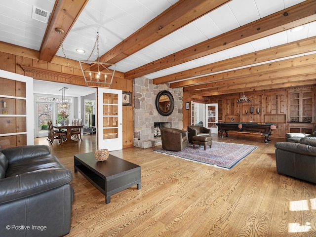 living room with beamed ceiling, wood walls, wood finished floors, and visible vents