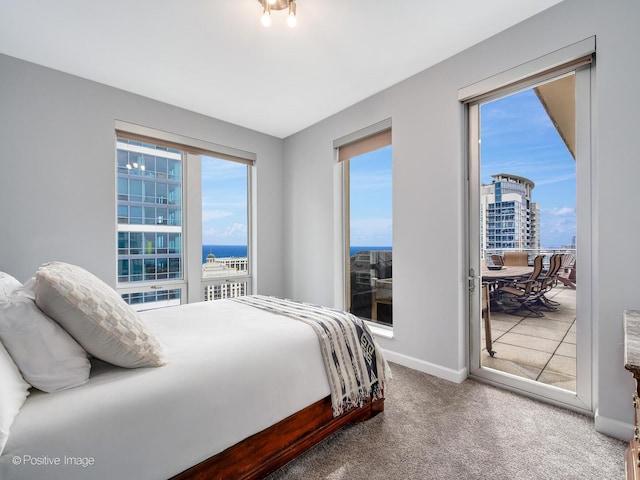 carpeted bedroom with access to outside, baseboards, a water view, and multiple windows