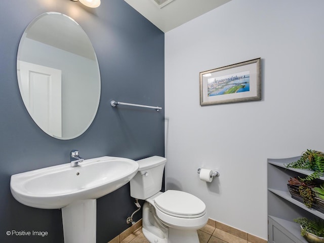 bathroom with toilet, baseboards, and tile patterned flooring