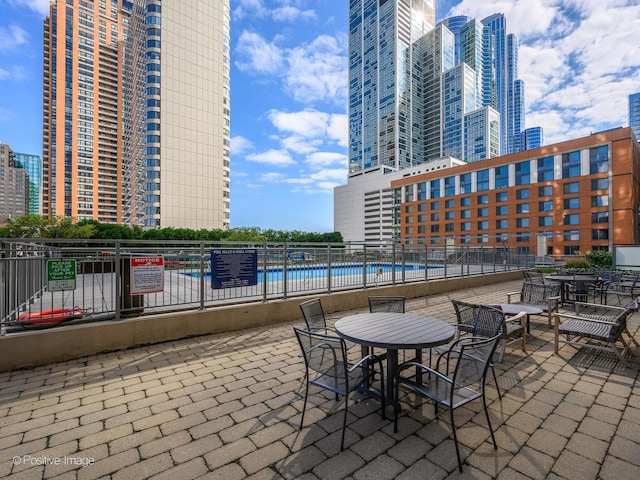 view of patio / terrace featuring fence, a city view, and a community pool